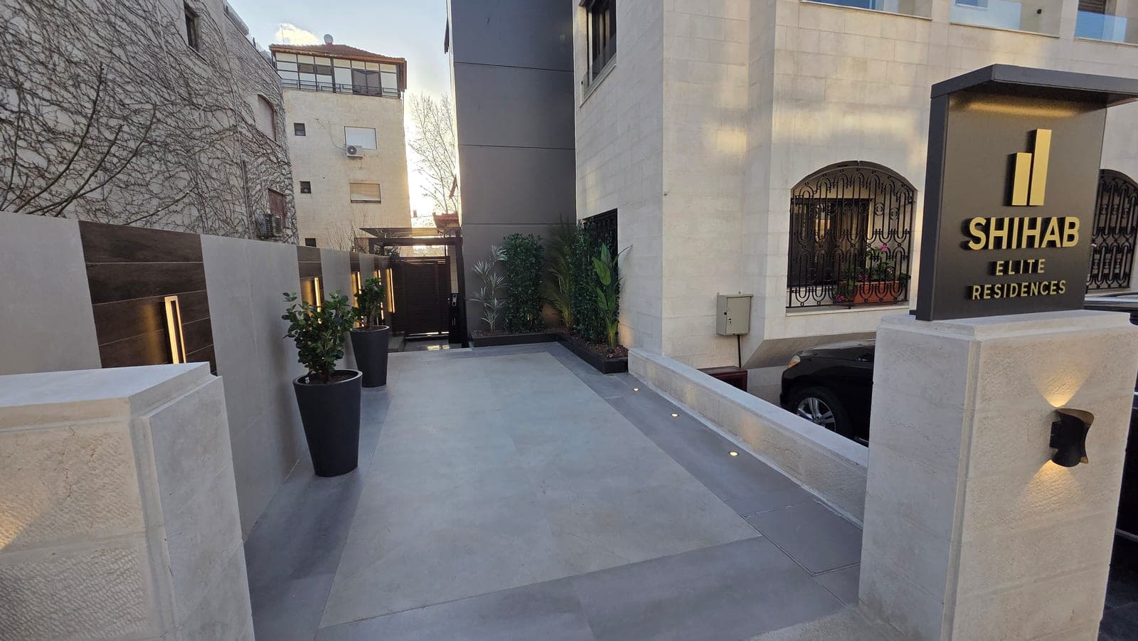 The branded SHIHAB Elite Residences arrival walkway with marble paving, integrated lighting, and planters
