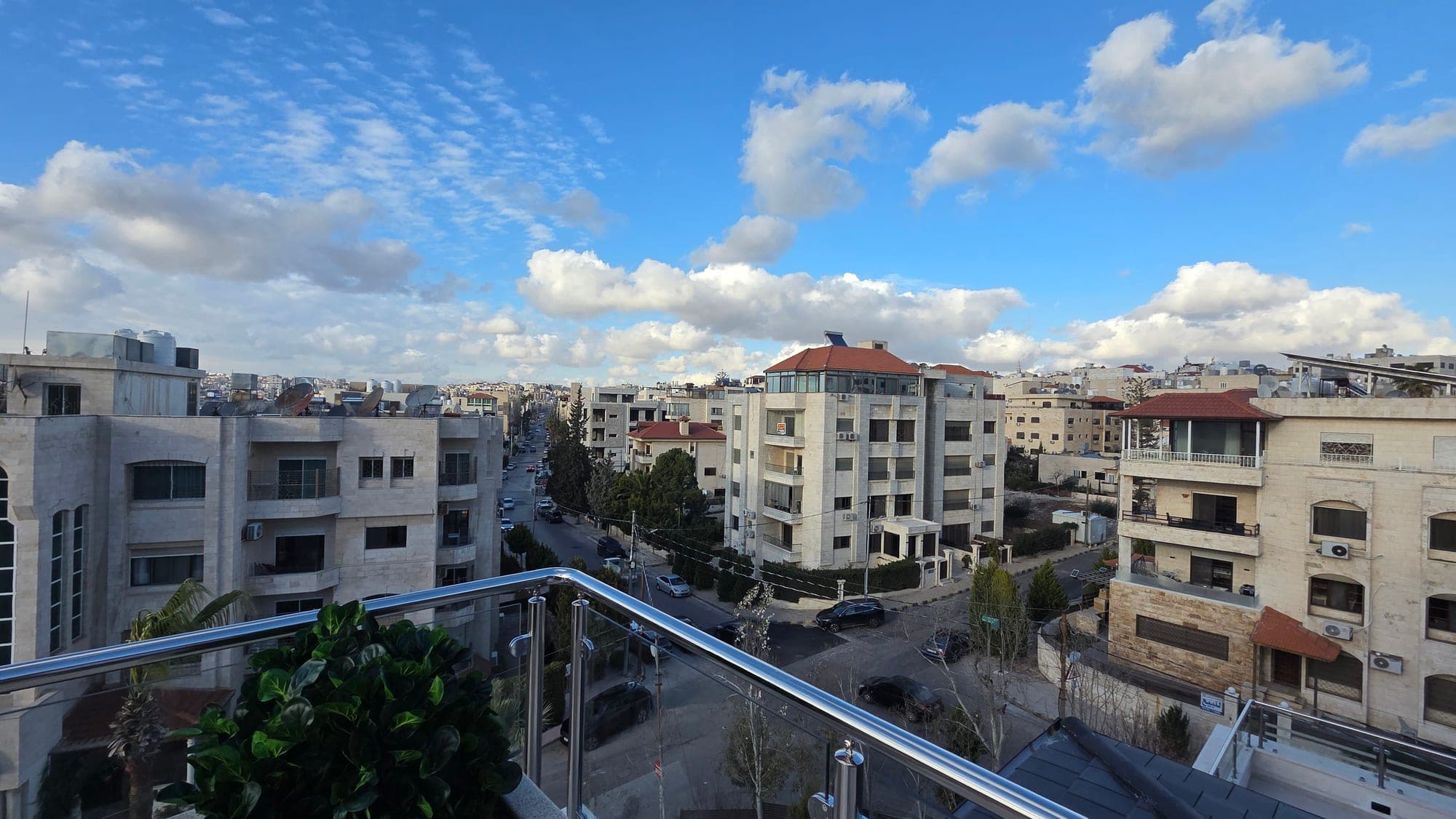 Open panoramic view from a rooftop terrace over Um Uthaina under open sky, with no adjacent building blocking the horizon